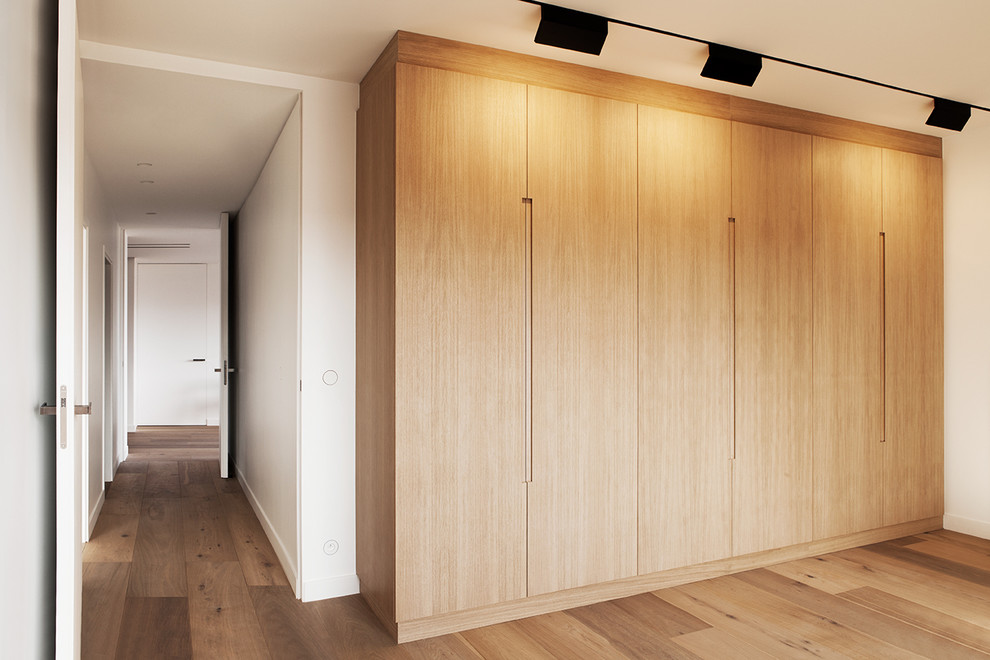 Modelo de armario unisex actual de tamaño medio con suelo de madera clara y puertas de armario de madera clara