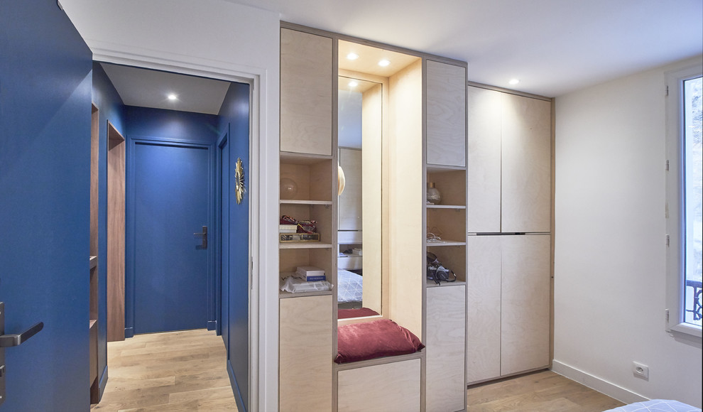 Ejemplo de armario unisex pequeño con armarios con rebordes decorativos, puertas de armario de madera clara y suelo de madera clara