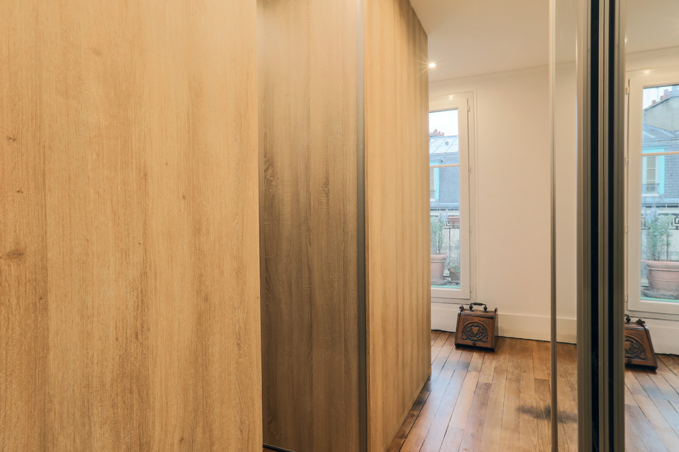 Foto de vestidor unisex actual grande con armarios con paneles lisos, puertas de armario de madera clara y suelo de madera en tonos medios