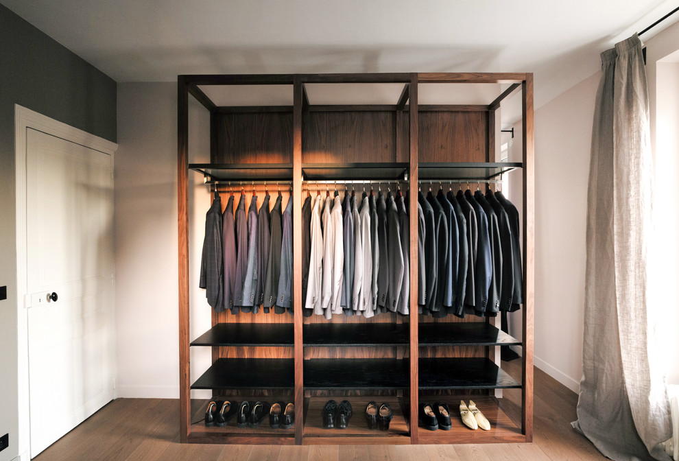 Diseño de vestidor de hombre actual pequeño con armarios abiertos, puertas de armario negras, suelo de madera oscura y suelo marrón