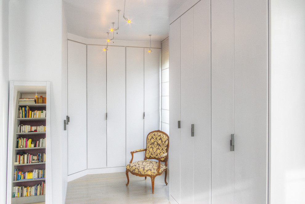 Diseño de vestidor unisex tradicional renovado grande con puertas de armario blancas y suelo de madera clara