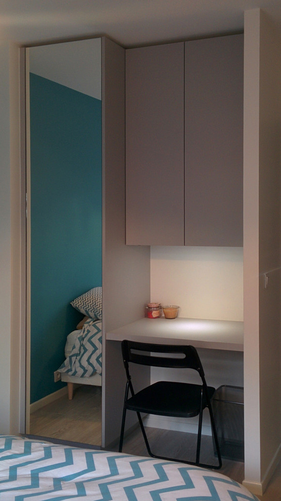 This is an example of a small contemporary gender neutral standard wardrobe in Grenoble with beaded cabinets, grey cabinets and light hardwood flooring.