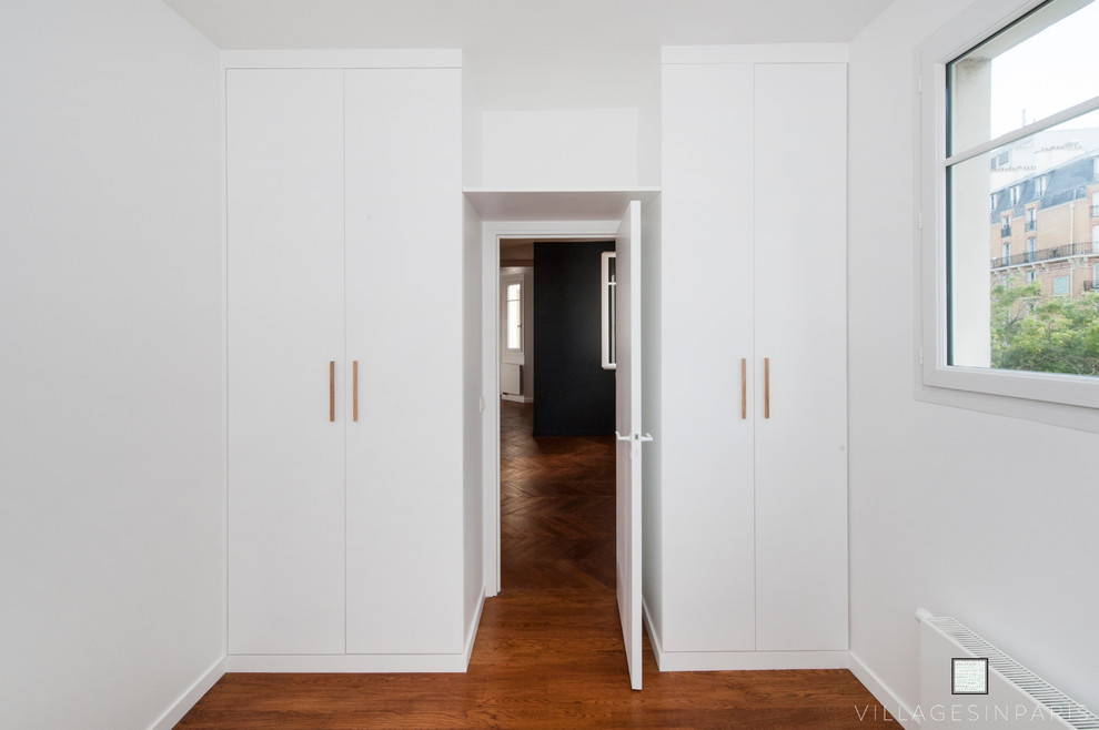 Ispirazione per un armadio o armadio a muro unisex contemporaneo di medie dimensioni con ante bianche e pavimento in legno massello medio