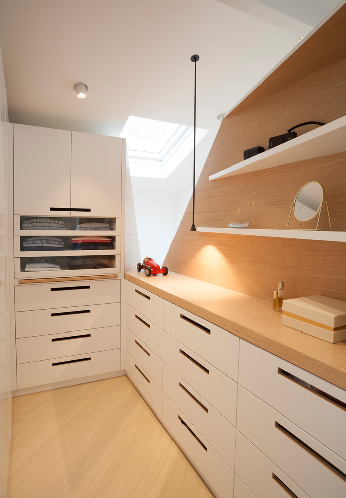 Réalisation d'un dressing design pour un homme avec un placard à porte plane, des portes de placard blanches et un sol en bois clair.