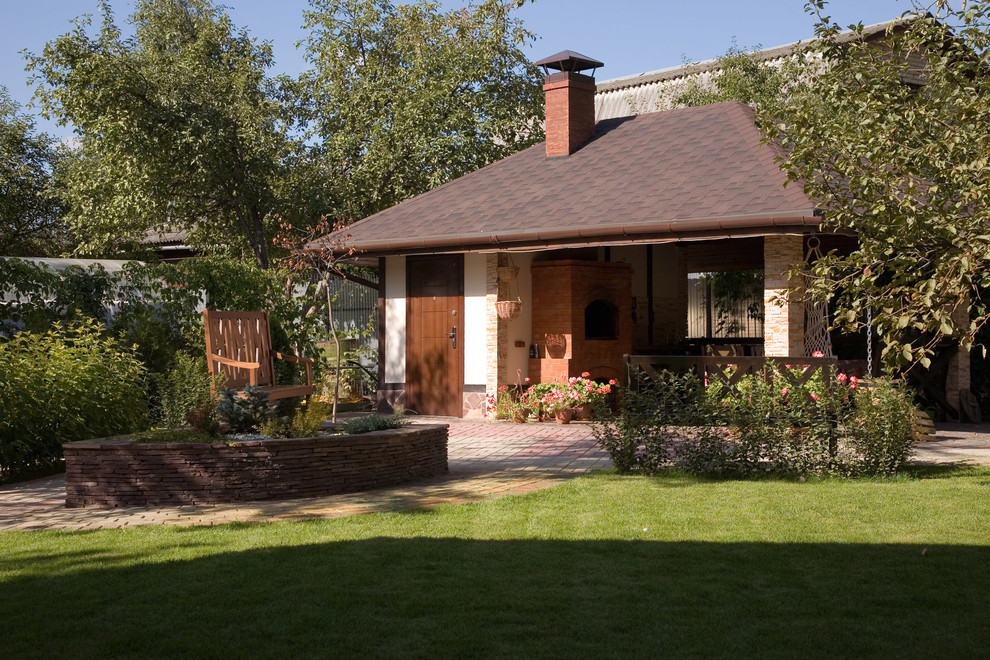 Foto di un grande patio o portico country in cortile con pavimentazioni in pietra naturale e un parasole