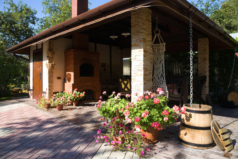 This is an example of a large farmhouse courtyard patio in Moscow with an outdoor kitchen, natural stone paving and an awning.