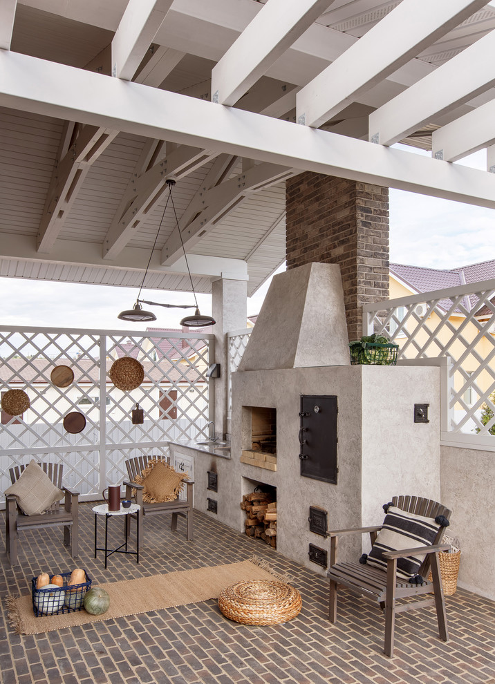 Cette photo montre une terrasse arrière méditerranéenne de taille moyenne avec une cuisine d'été, une pergola et des pavés en brique.