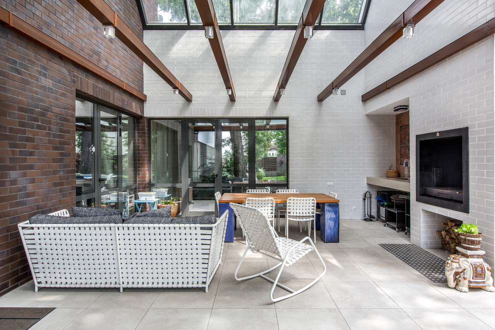 Cette image montre une grande terrasse latérale design avec une cuisine d'été et une extension de toiture.