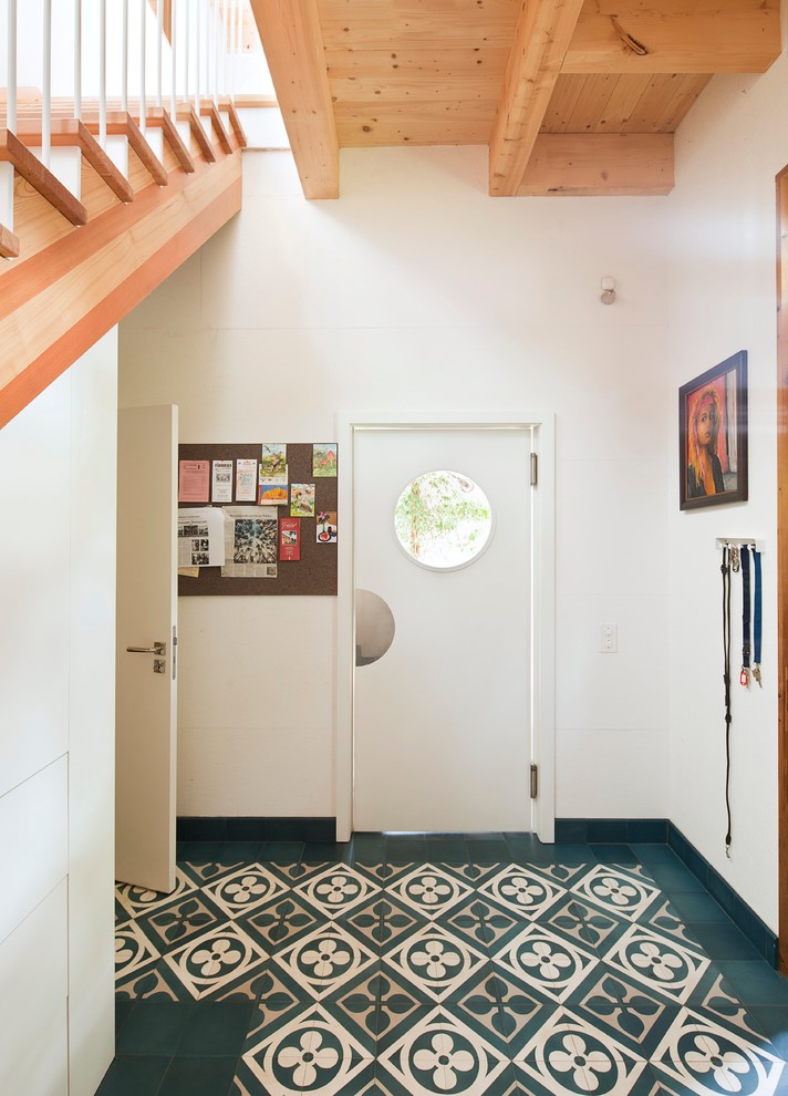 На фото: узкая прихожая среднего размера в скандинавском стиле с белой входной дверью, белыми стенами, одностворчатой входной дверью и полом из керамической плитки