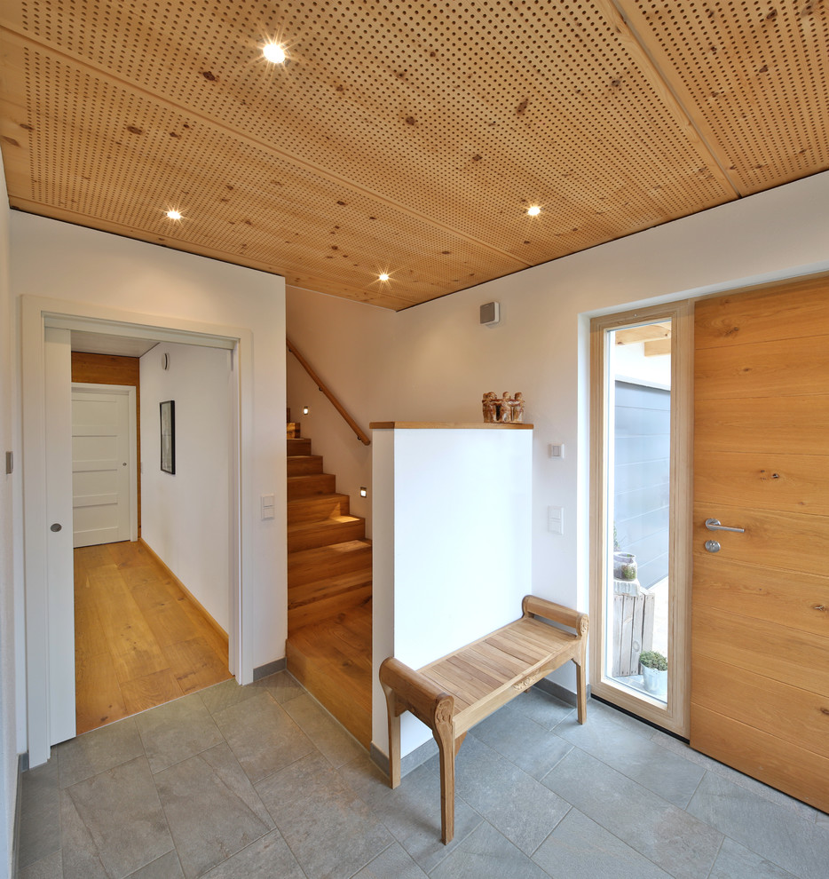 Источник вдохновения для домашнего уюта: фойе среднего размера в современном стиле с белыми стенами, одностворчатой входной дверью, входной дверью из дерева среднего тона, серым полом и полом из сланца