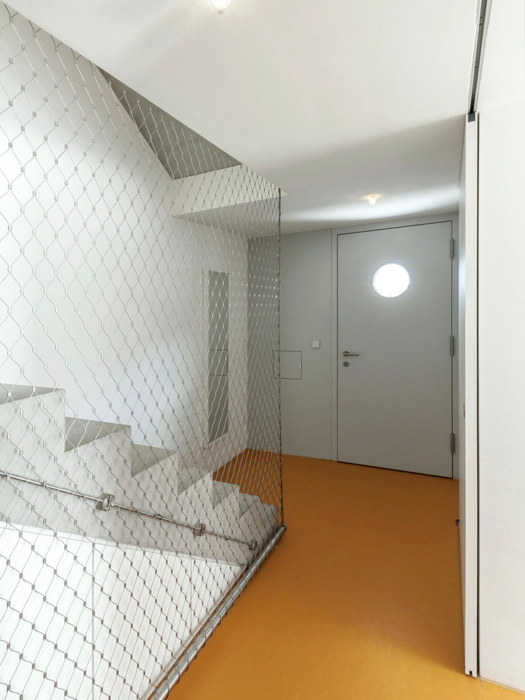 Cette photo montre une petite porte d'entrée tendance avec un mur blanc, une porte simple, une porte blanche et un sol orange.