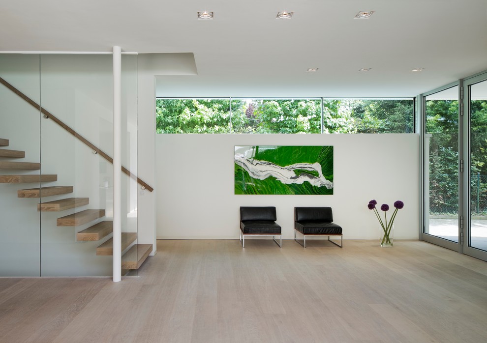 Modernes Foyer mit weißer Wandfarbe, hellem Holzboden und Haustür aus Glas in Hamburg
