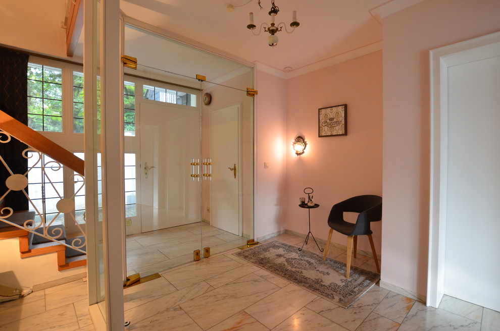 Cette image montre un hall d'entrée traditionnel de taille moyenne avec un mur rose, un sol en marbre, une porte simple, une porte blanche et un sol blanc.