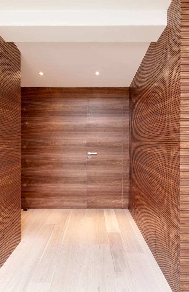 На фото: узкая прихожая среднего размера в современном стиле с светлым паркетным полом, одностворчатой входной дверью, входной дверью из дерева среднего тона и коричневыми стенами