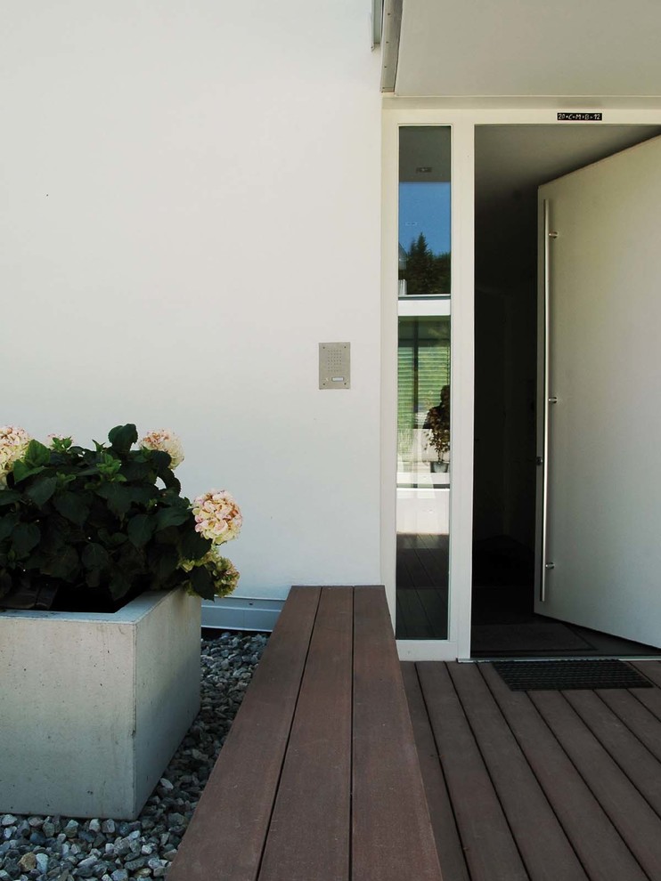 Imagen de puerta principal contemporánea de tamaño medio con paredes blancas, suelo de madera oscura, puerta simple, puerta blanca y suelo marrón
