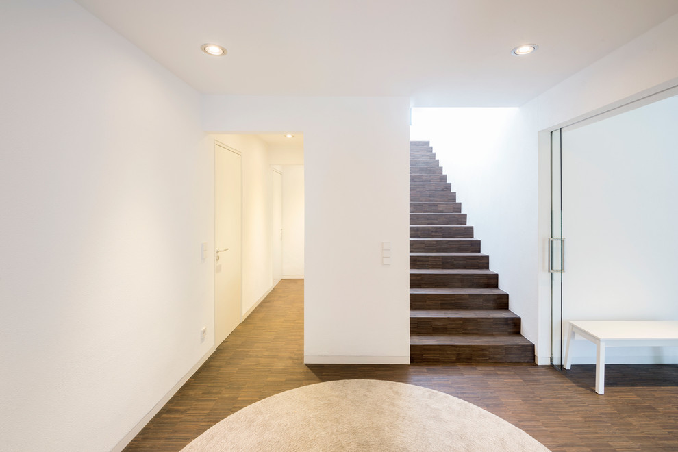 Idee per un corridoio minimal di medie dimensioni con pareti bianche e parquet scuro