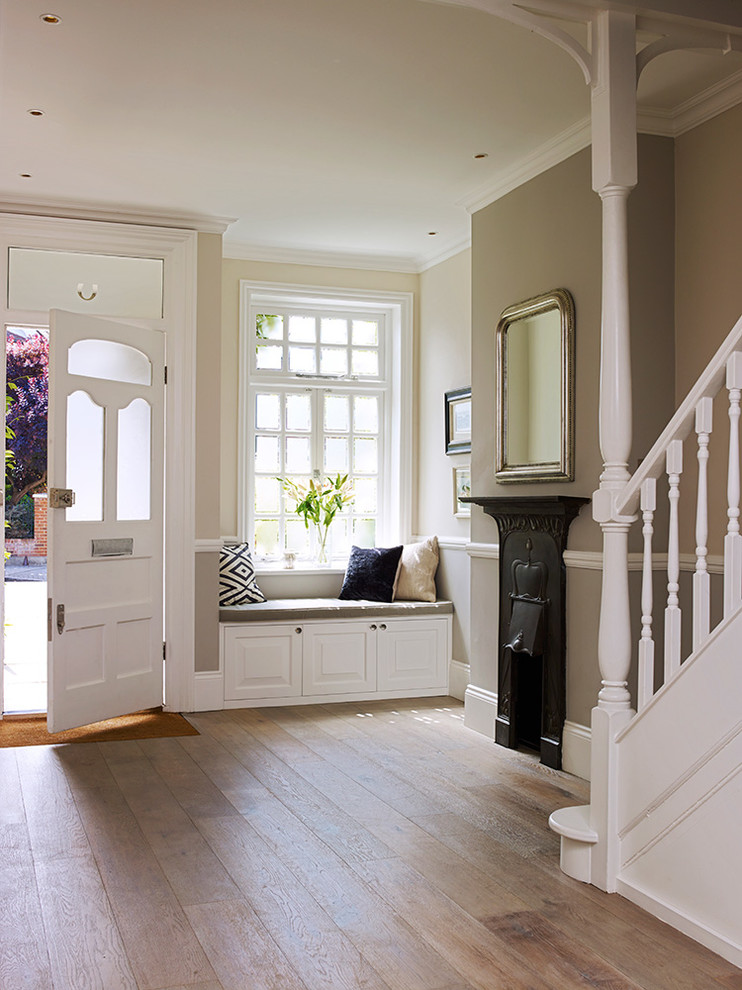 Klassisches Foyer mit grauer Wandfarbe, hellem Holzboden, Einzeltür und weißer Haustür in London