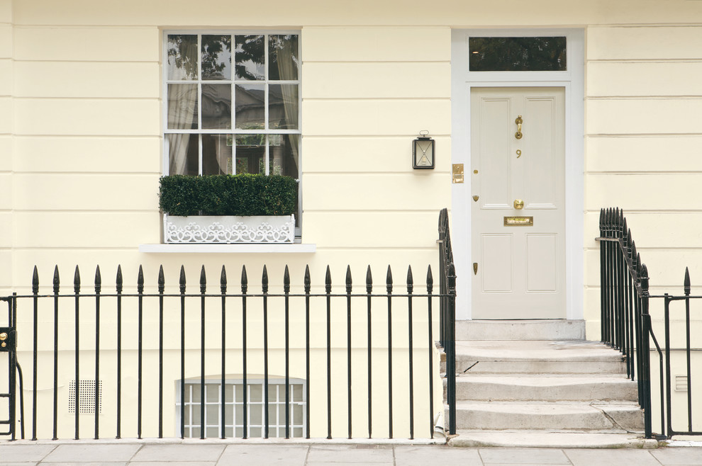 Mittelgroße Klassische Haustür mit gelber Wandfarbe, Einzeltür und Betonboden in Sonstige