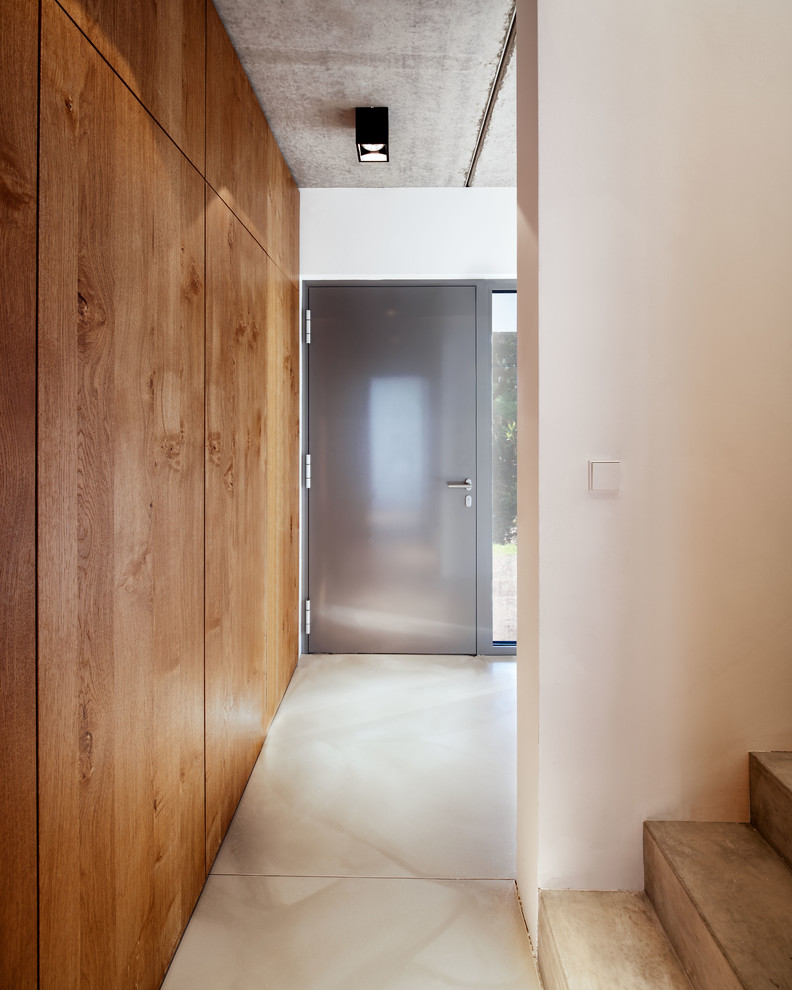 Modern inredning av ett mellanstort kapprum, med vita väggar, en enkeldörr och en grå dörr