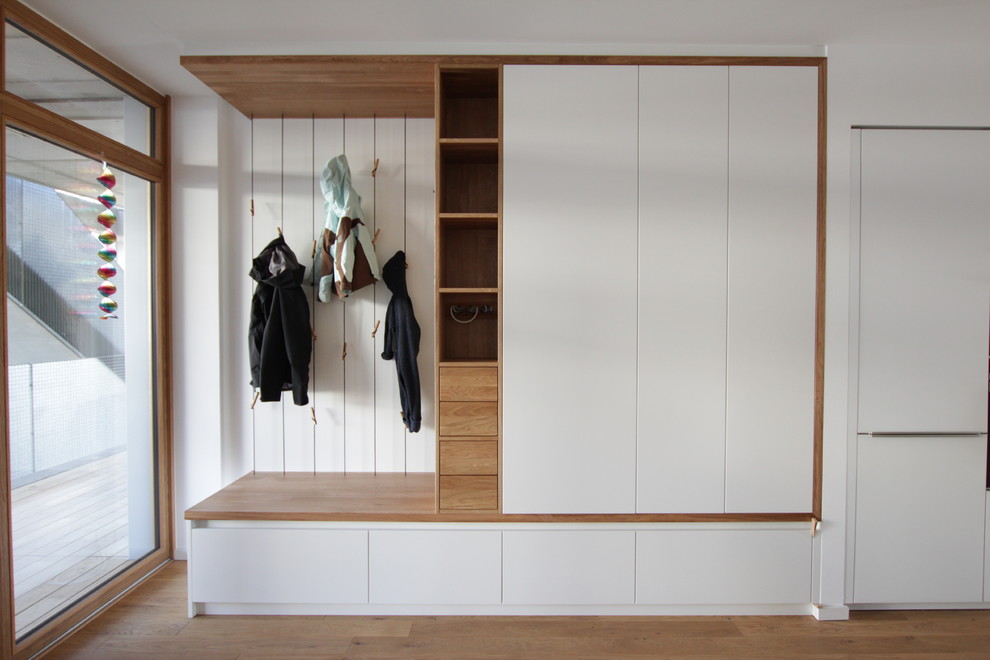 Ejemplo de vestíbulo posterior minimalista de tamaño medio con paredes blancas, suelo de madera oscura y suelo marrón