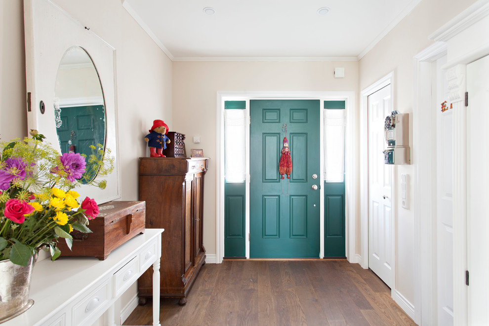 Diseño de distribuidor clásico con paredes beige, suelo de madera en tonos medios, puerta simple y puerta verde