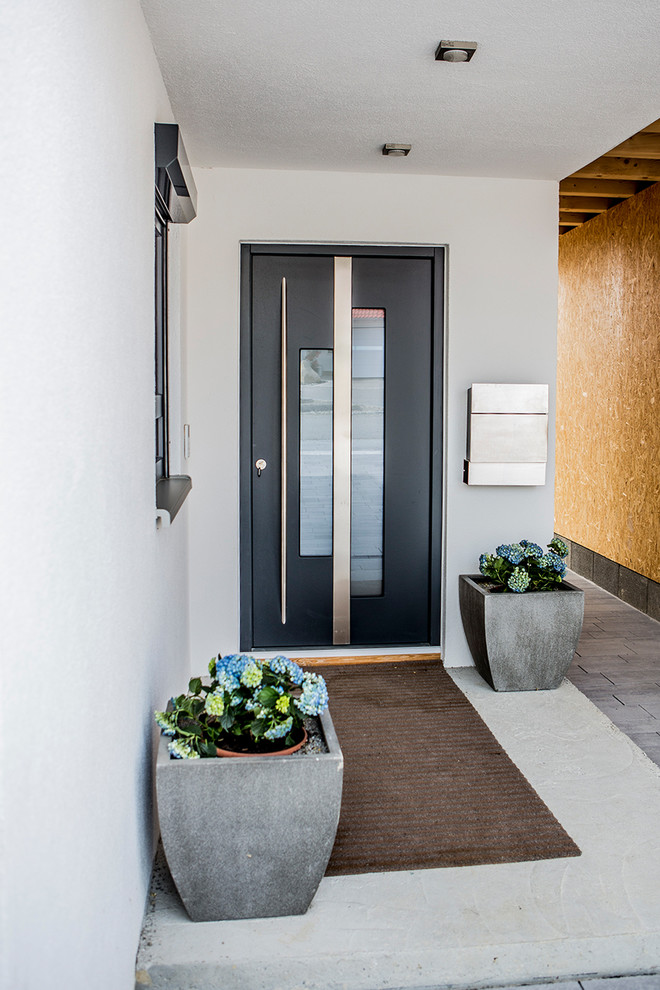 Inspiration för små moderna ingångspartier, med vita väggar, betonggolv, en enkeldörr, en svart dörr och grått golv