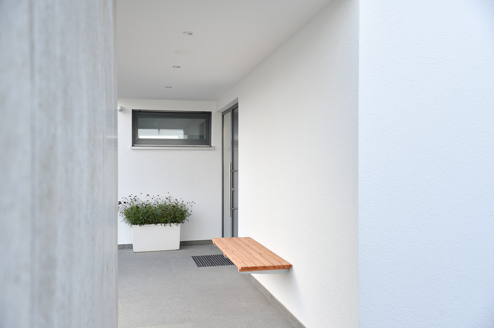 Immagine di una porta d'ingresso minimal di medie dimensioni con pareti bianche, pavimento in cemento, una porta a due ante, una porta grigia e pavimento grigio