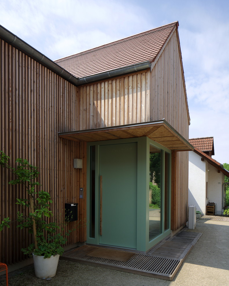 Foto på en mellanstor minimalistisk ingång och ytterdörr, med en enkeldörr, en grön dörr och brunt golv