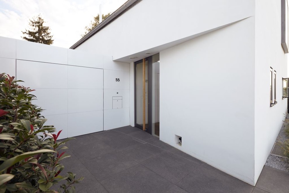 Ejemplo de puerta principal actual con paredes blancas, suelo de cemento, puerta simple y puerta de vidrio