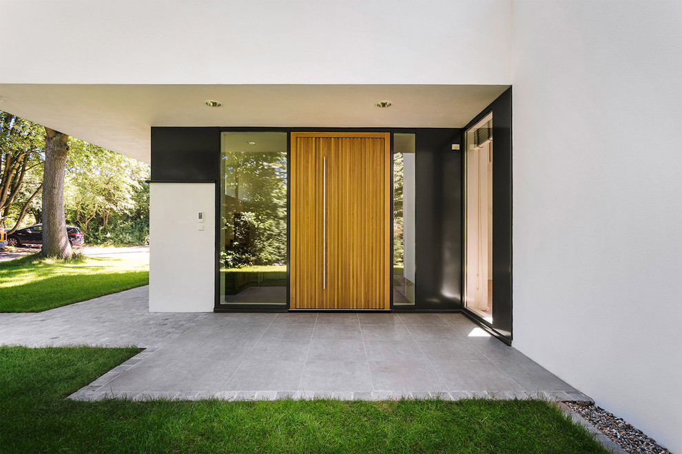 Пример оригинального дизайна: большая входная дверь в современном стиле с белыми стенами, одностворчатой входной дверью и входной дверью из светлого дерева
