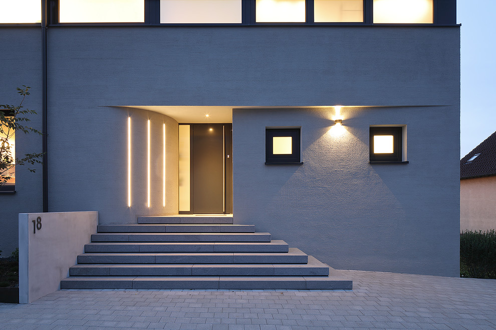 Пример оригинального дизайна: маленькая входная дверь в стиле модернизм с серыми стенами, одностворчатой входной дверью, черной входной дверью и серым полом для на участке и в саду