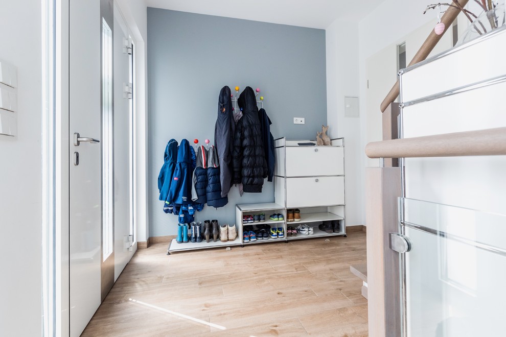 This is an example of a medium sized scandi boot room in Frankfurt with grey walls, medium hardwood flooring, a single front door, a white front door and brown floors.