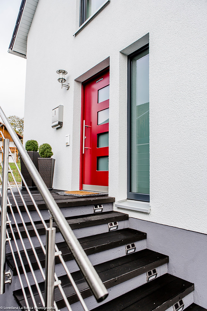 Mittelgroße Moderne Haustür mit weißer Wandfarbe, Einzeltür, roter Haustür und schwarzem Boden in Sonstige