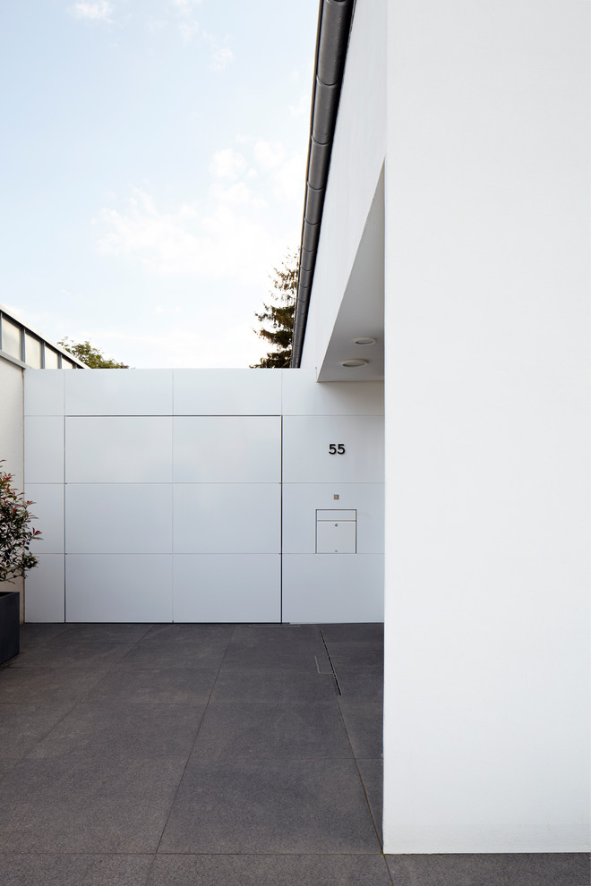 Aménagement d'une entrée contemporaine avec un mur blanc, sol en granite, une porte simple et une porte blanche.