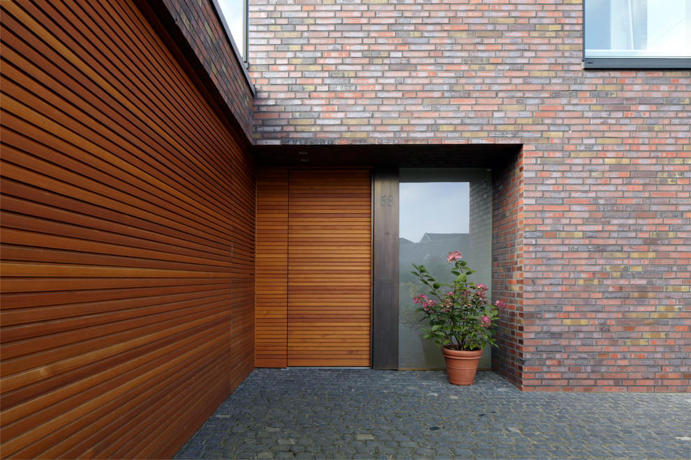Diseño de entrada moderna con puerta simple, puerta de madera en tonos medios y suelo gris