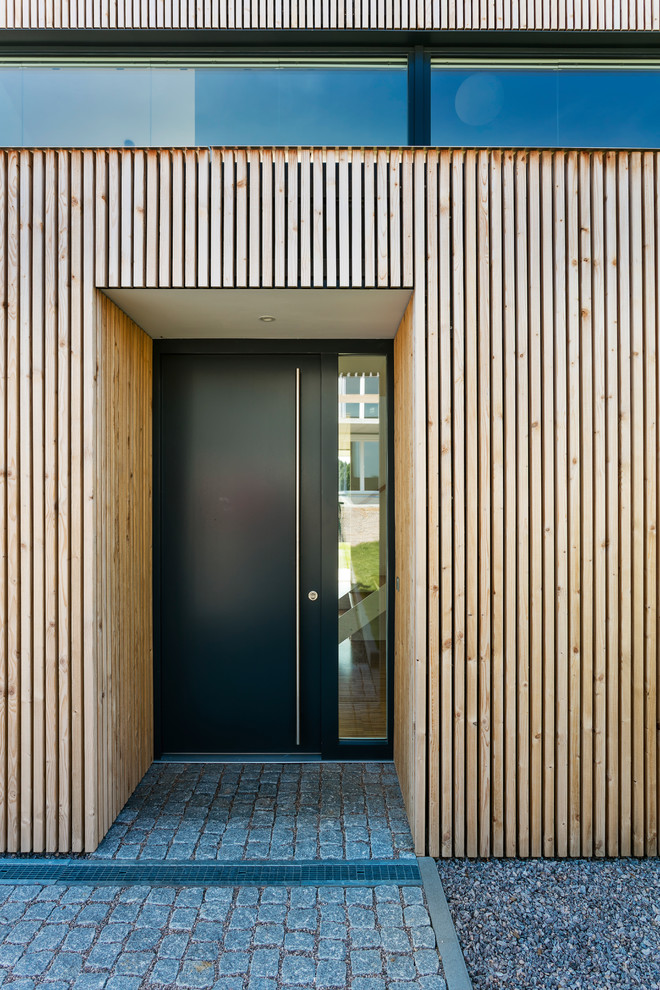 This is an example of a medium sized contemporary front door in Other with brown walls, a single front door, a black front door and grey floors.