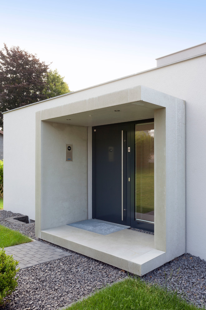 Imagen de puerta principal actual de tamaño medio con paredes grises, suelo de cemento, puerta simple y puerta negra