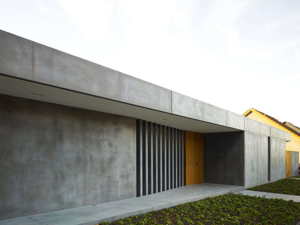 Immagine di una porta d'ingresso industriale di medie dimensioni con pareti grigie, pavimento in cemento, una porta singola, una porta in legno bruno e pavimento grigio
