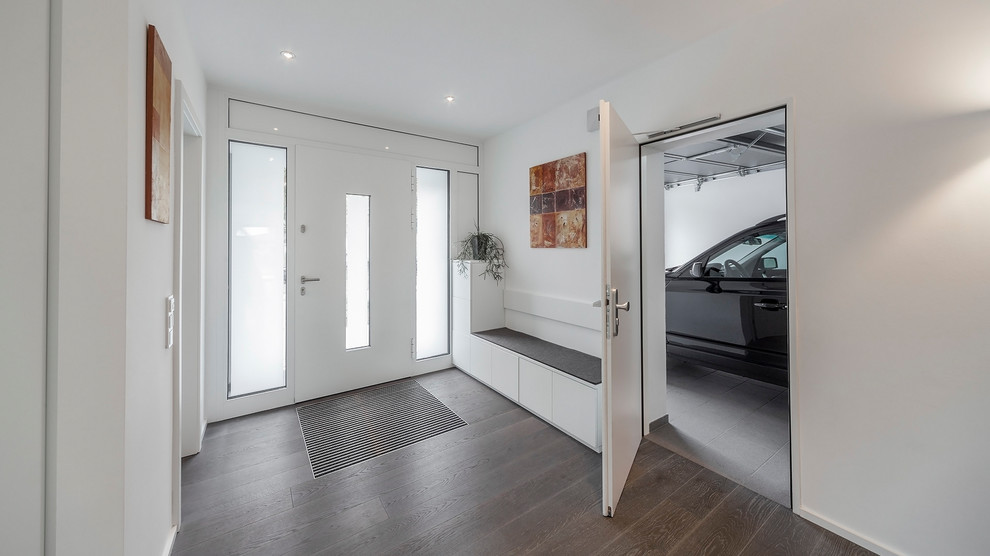 Imagen de vestíbulo posterior minimalista de tamaño medio con paredes blancas, suelo de madera oscura, puerta simple, puerta blanca y suelo marrón