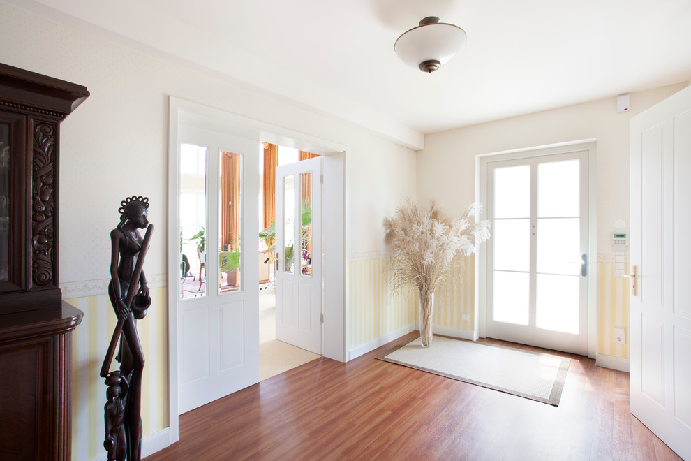Foto de puerta principal campestre de tamaño medio con paredes amarillas, puerta simple, puerta de vidrio, suelo de madera en tonos medios y suelo marrón