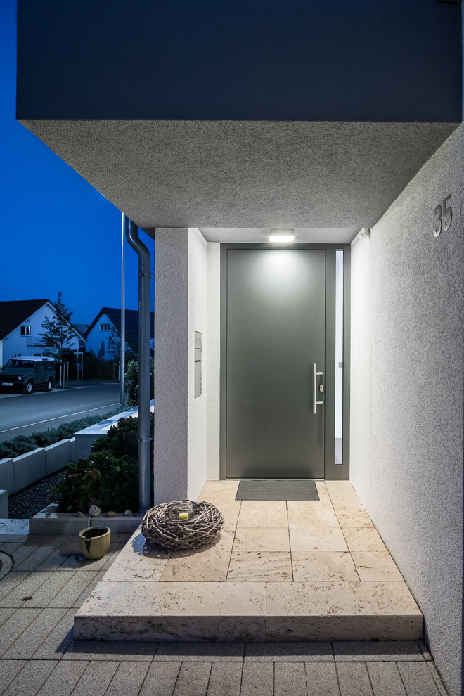 Réalisation d'une porte d'entrée design de taille moyenne avec un mur blanc, un sol en travertin, une porte simple, une porte grise et un sol beige.