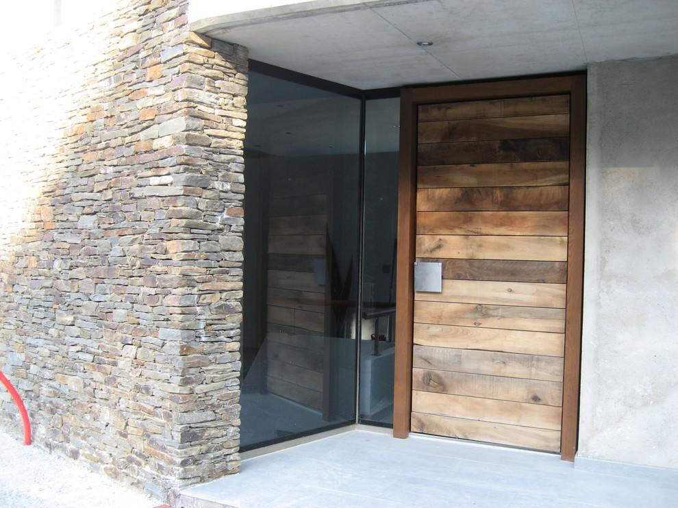 他の地域にあるコンテンポラリースタイルのおしゃれな玄関ドア (グレーの壁、コンクリートの床、濃色木目調のドア) の写真