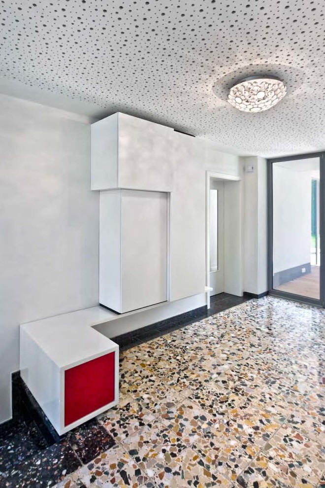 Cette image montre une entrée design de taille moyenne avec un vestiaire, un mur blanc, un sol en terrazzo et une porte en verre.