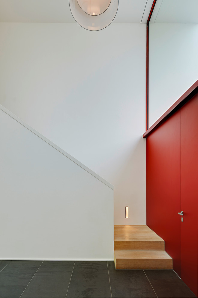 Idéer för en modern ingång och ytterdörr, med vita väggar, en enkeldörr, en röd dörr och betonggolv