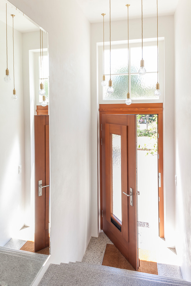 Bild på en mellanstor funkis entré, med vita väggar, en enkeldörr och en brun dörr