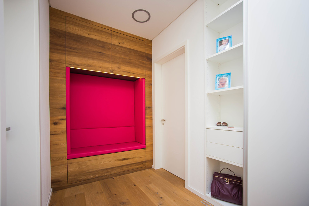 Cette photo montre une entrée tendance de taille moyenne avec un vestiaire, un mur blanc, un sol en bois brun et un sol marron.