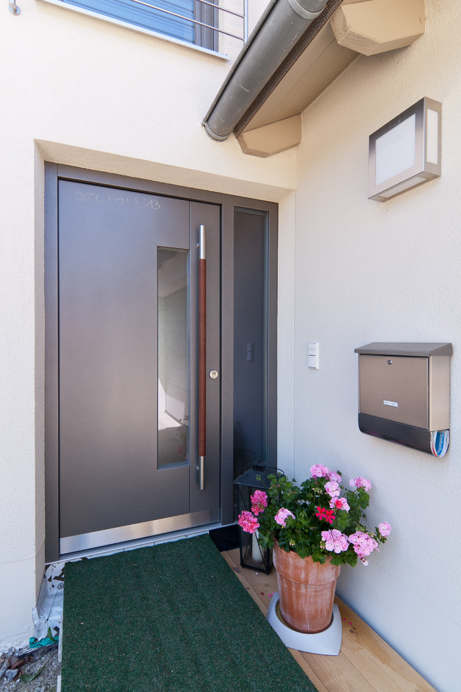 Diseño de puerta principal contemporánea de tamaño medio con paredes blancas, suelo de madera en tonos medios, puerta simple, puerta gris y suelo marrón