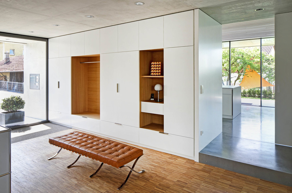 Ejemplo de distribuidor minimalista con paredes blancas, suelo de madera en tonos medios y suelo marrón