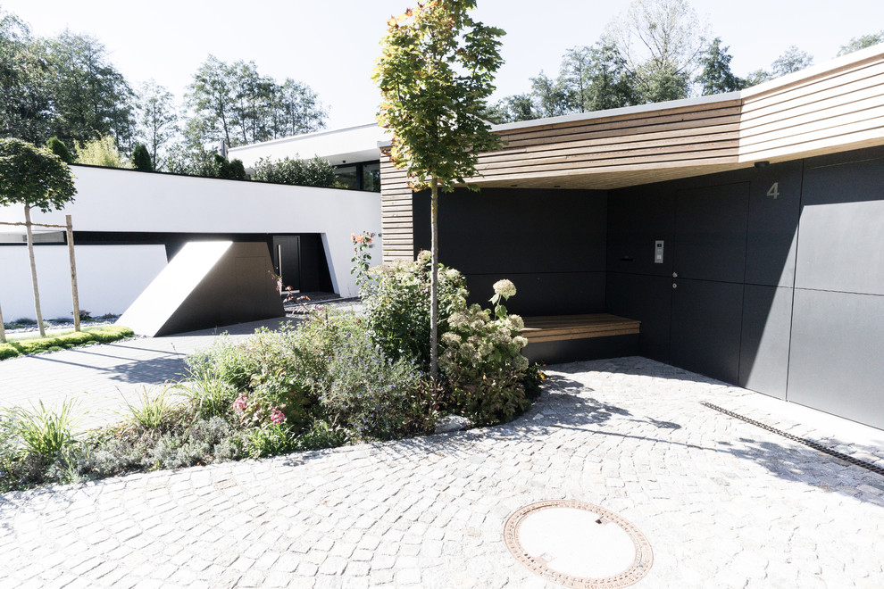Cette image montre une grande entrée design avec un vestiaire, un mur noir, sol en granite, une porte simple, une porte noire et un sol gris.