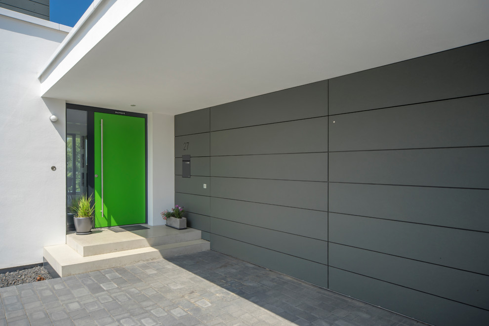 На фото: входная дверь в современном стиле с серыми стенами, одностворчатой входной дверью, зеленой входной дверью и бетонным полом